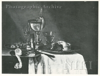 Olives and a Lemon on Pewter Plates, a Glass Goblet, an Overturned Silver Beaker, a Nautilus Shell Mounted in Silver with Figurines, a Glass of Wine and a Pie on a Pewter Dish